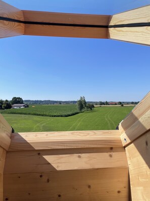 A wooden structure with a view of a green field and distant buildings. - Bavasol – Your Temporary Bavarian Retreat (Schechen)