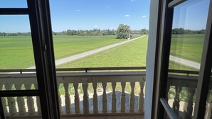 A view from a room with a balcony, overlooking a green field and a clear sky. - Bavasol – Your Temporary Bavarian Retreat (Schechen)