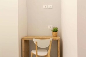 A corner desk with a chair, a potted plant, and two wall sockets. - Athens House • Near the Duomo [Loreto-Duomo] (Milano)