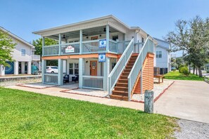 A two-story building with a balcony, a staircase, and a sign indicating it is a rental property. - Cheeky Crab A - 2 Bedroom Coastal Cottage Steps from the Beach (Garden City Beach)