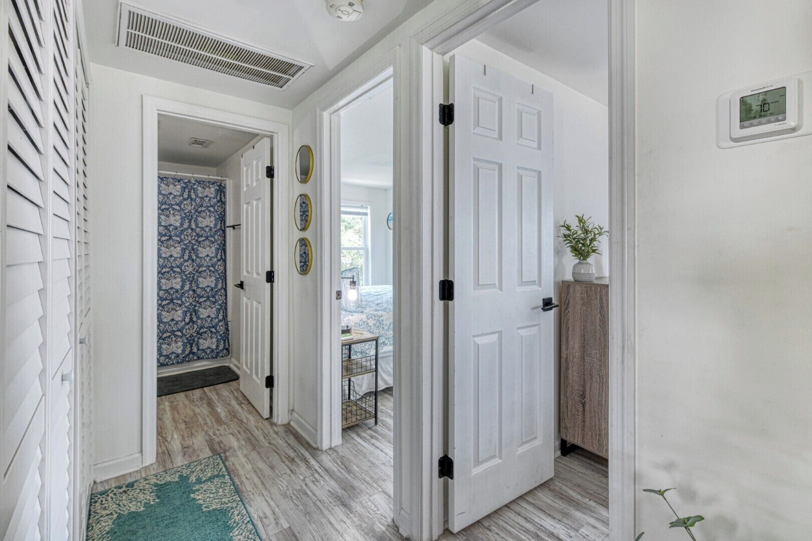 A hallway with white doors, a patterned wall, and a wooden floor.