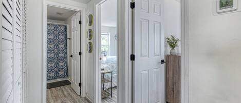 A hallway with white doors, a patterned wall, and a wooden floor.