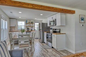 Eine moderne Küche mit weißen Schränken, Holzboden und einem Essbereich mit Holztisch und -stühlen.