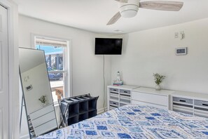 Quarto com cama, ventilador de teto, televisão, janela e cômoda.