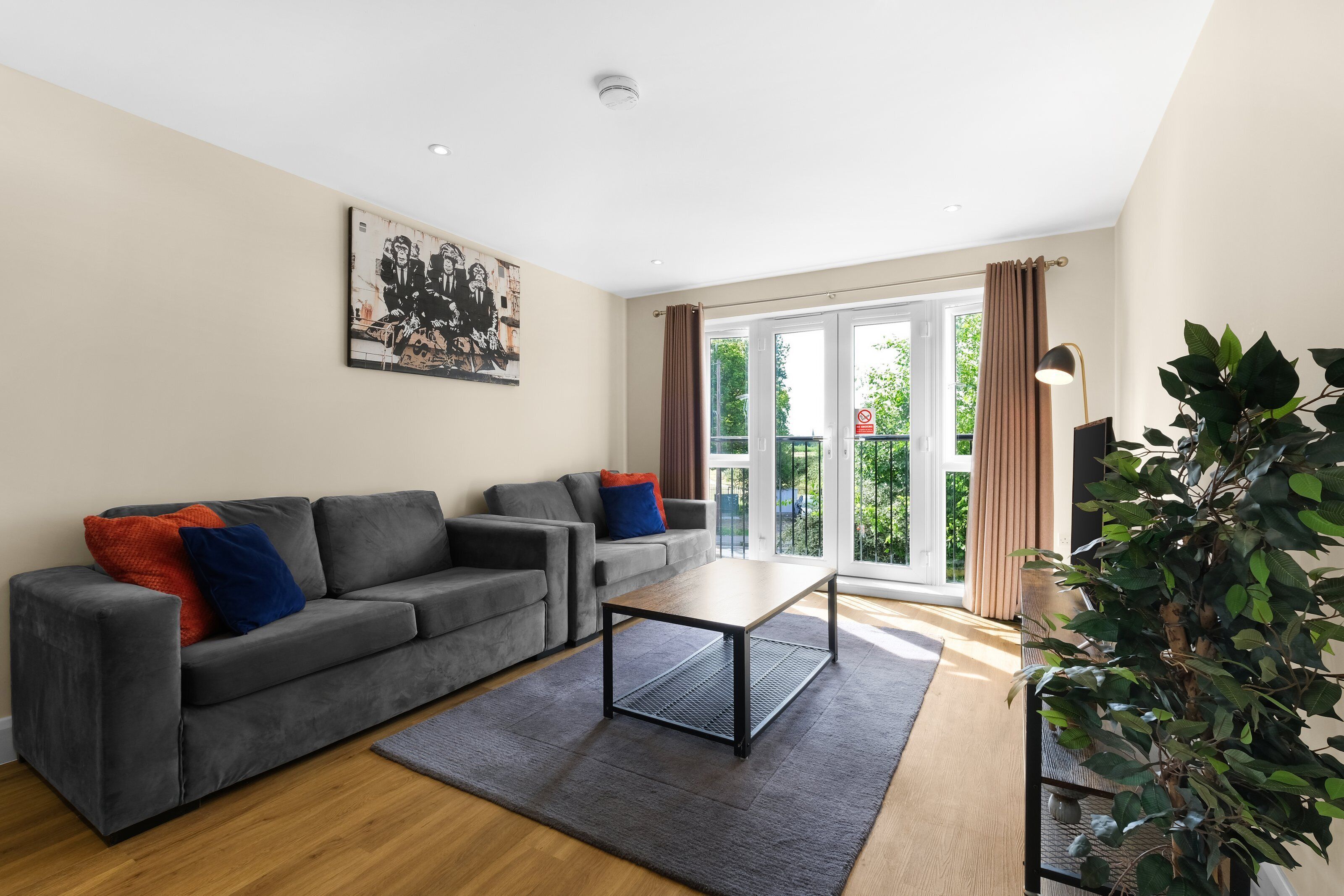 A modern living room with a grey sofa, a coffee table, and a large window with curtains.