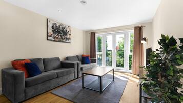 A modern living room with a grey sofa, a coffee table, and a large window with curtains.