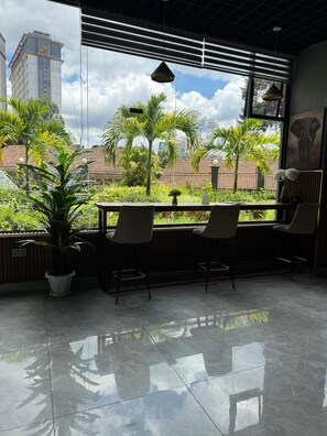 A modern interior with a large window overlooking a garden and a cityscape.