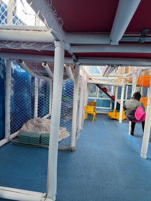 A play area with a netted enclosure, a blue floor, and a yellow chair.