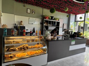 A coffee shop interior with a display case of pastries and a counter with a coffee machine.