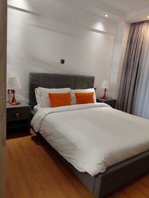 A hotel room with a large bed, two bedside tables, and a headboard.