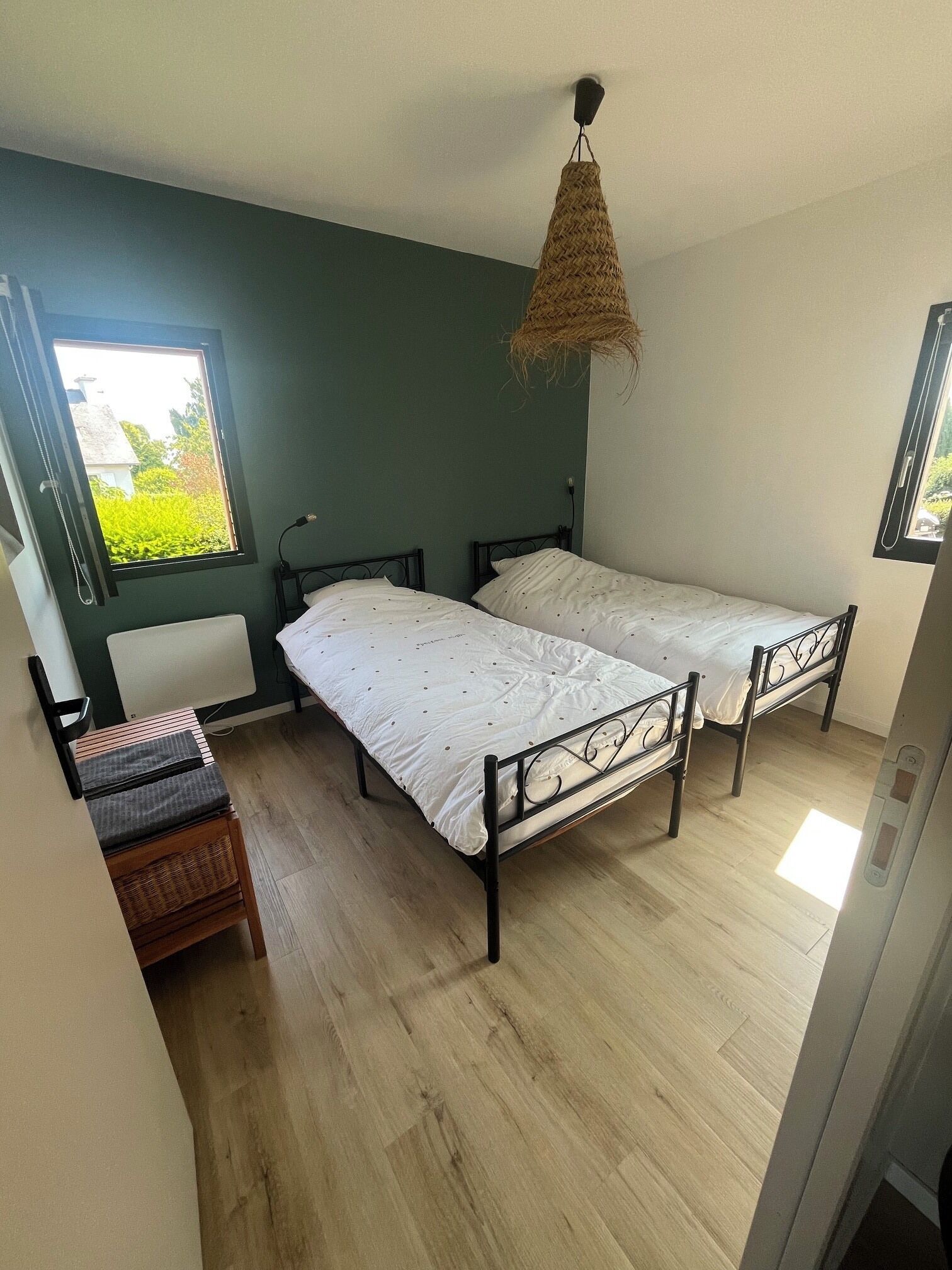 Una habitación con dos camas, un escritorio y una ventana con vistas al verde.