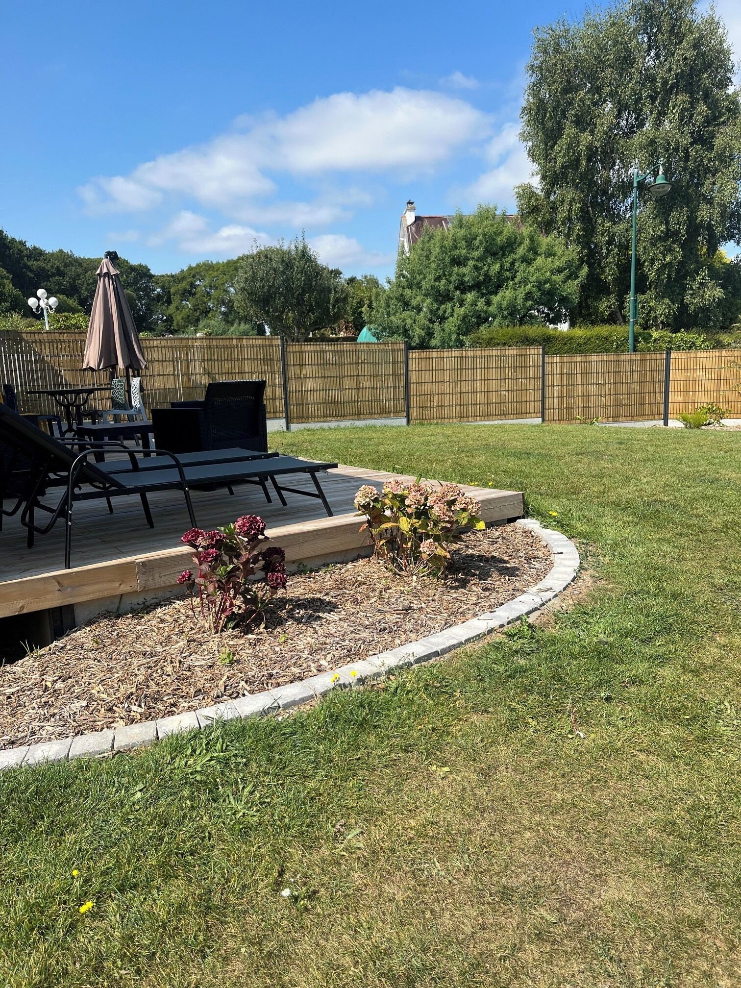 A backyard with a patio area, outdoor furniture, and a wooden deck.