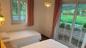 Een slaapkamer met twee bedden, een raam met gordijnen en een hanglamp.