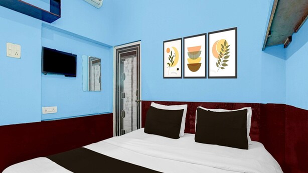 A hotel room with a bed, a wall-mounted TV, a door, and three framed pictures. - Hotel O Singar Nagar Metro Station Lucknow (Lucknow)