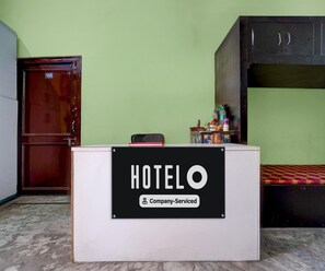 Ein Hotelrezeptionstresen mit einem Schild, das angibt, dass er betrieblich genutzt wird. Im Hintergrund ist eine Holztür und ein Etagenbett zu sehen.
