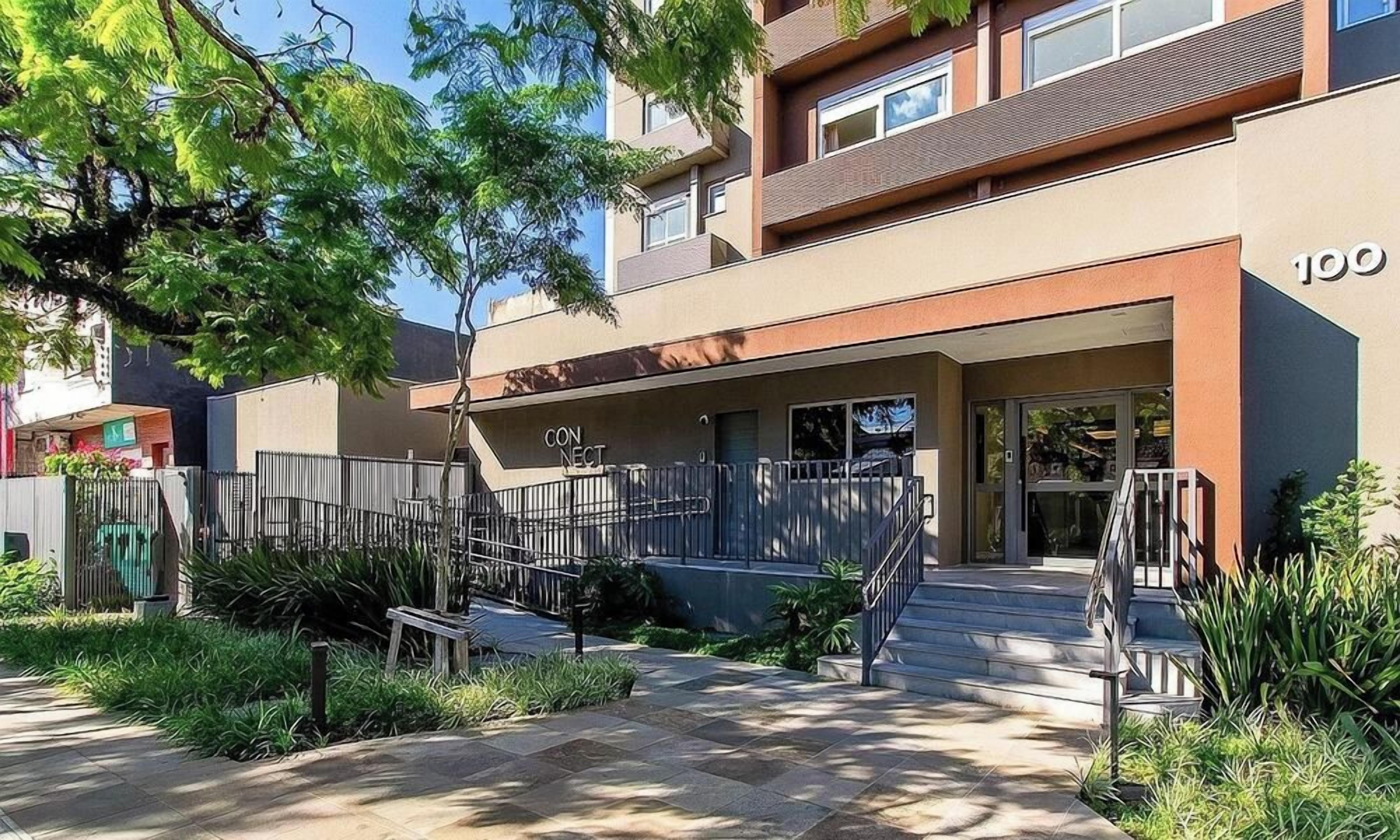 Um edifício moderno com telhado plano, entrada visível e escadaria que leva à entrada.
