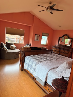 A bedroom with a bed, a dresser, a vanity, a chair, and a ceiling fan. - Family-Ready Downtown Cedar Cottage (Fairbanks)