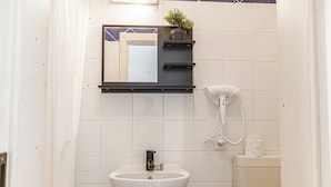 Une salle de bain avec un lavabo blanc, un miroir, un téléphone et des toilettes.