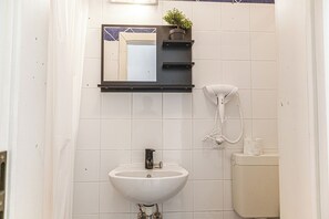 Ein Badezimmer mit einem weißen Waschbecken, einem Spiegel, einem Telefon und einer Toilette.