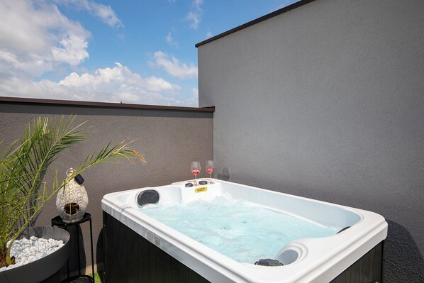 Ein Whirlpool mit zwei Düsen, ein kleiner Tisch mit einer Dekoration und eine Topfpflanze daneben.