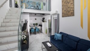 A modern interior with a staircase, a living area with a blue sofa, a dining area, and a kitchen. - Villa PalmDora – New Vacation Home with Private Pool & Hot Tub in Istria (Marčana)