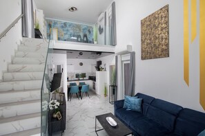Ein modernes Interieur mit Treppe, einem Wohnbereich mit blauem Sofa, einem Essbereich und einer Küche.