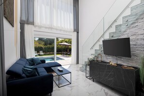 Ein modernes Wohnzimmer mit Sofa, Couchtisch und Fernseher, der an einer Steinwand angebracht ist.