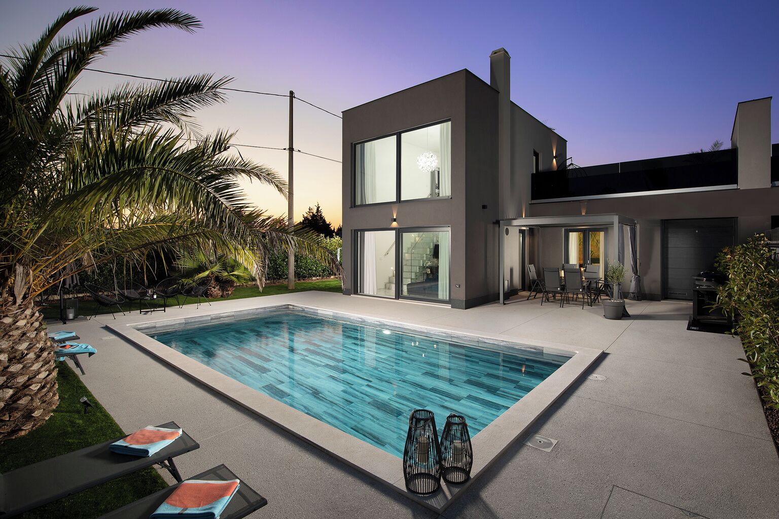 A modern two-story house with a swimming pool, outdoor seating, and a well-maintained garden.