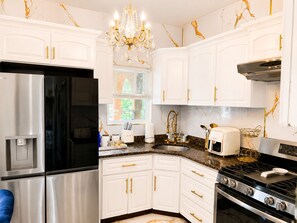 A kitchen with white cabinets, a stainless steel refrigerator, a gas stove, and a chandelier. - Royal 3-bedroom apartment/Wifi/15 min NYC/Bus stop 2 min/8 people (West New York)