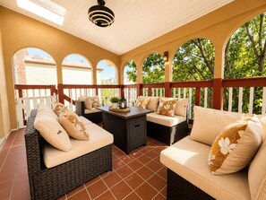 Ein überdachter Patio-Bereich mit Korbmöbeln, einem Tisch und einem Blumentopf.