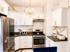 Eine moderne Küche mit weißen Schränken, einem Edelstahlkühlschrank, einem Gasherd und einem Einbauofen.