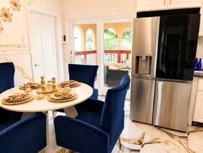 A modern kitchen with a stainless steel refrigerator, a dining table set for four, and blue chairs. - Royal 3-bedroom apartment/Wifi/15 min NYC/Bus stop 2 min/8 people (West New York)