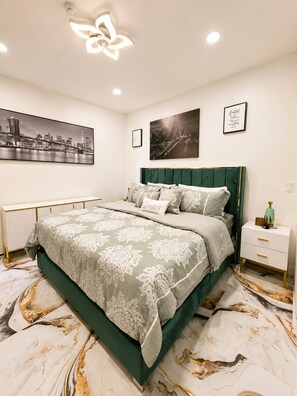 A modern bedroom with a green upholstered headboard, a marble-patterned floor, and artwork on the walls. - Royal 3-bedroom apartment/Wifi/15 min NYC/Bus stop 2 min/8 people (West New York)