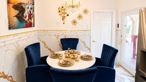 A dining room with a round table, blue chairs, a chandelier, and a painting on the wall. - Royal 3-bedroom apartment/Wifi/15 min NYC/Bus stop 2 min/8 people (West New York)