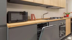 Une cuisine moderne équipée d’un four à micro-ondes, d’un four, d’un lave-vaisselle et de meubles de rangement en bois.