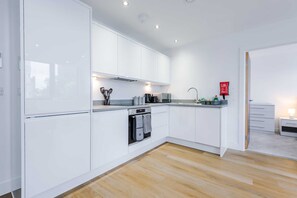A modern kitchen with white cabinets, a built-in oven, and a coffee machine. - NEW! Chic City Base - Old Trafford & MediaCityUK (Stretford)