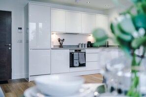 A modern kitchen with white cabinetry, a built-in oven, and a coffee machine. - NEW! Chic City Base - Old Trafford & MediaCityUK (Stretford)