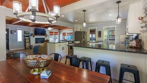 Une cuisine spacieuse avec une table à manger en bois, des tabourets de bar et un grand îlot central.