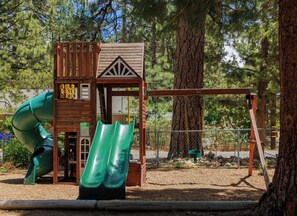 Ein Spielplatz mit Rutsche, Schaukeln und einer Kletterkonstruktion.