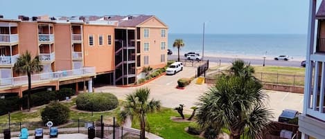 A residential building with a swimming pool, a beach view, and a parking area.
