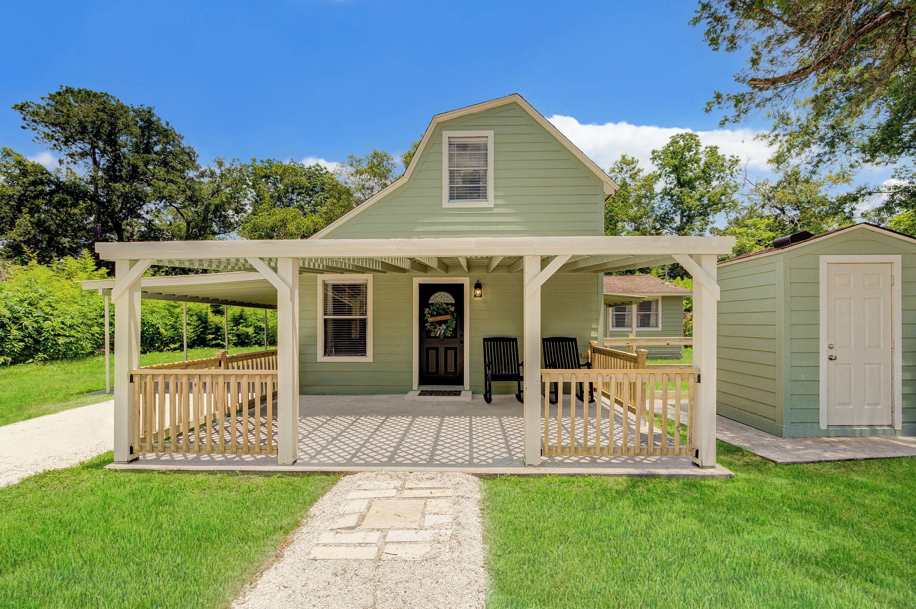 A two-story house with a porch, a small attached garage, and a pathway leading to the entrance.