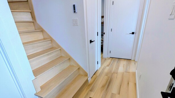 A staircase leading to a landing with a carpeted area, white walls, and a door leading to another room.
