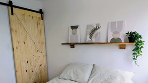 A bedroom with a bed, striped pillows, a wooden door, and wall art.
