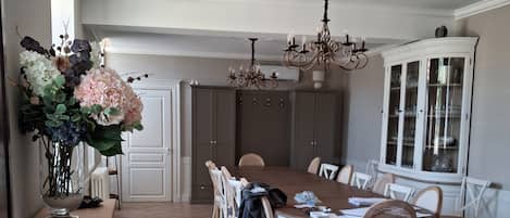 A dining room with a herringbone floor, a chandelier, and a cabinet with glass doors.