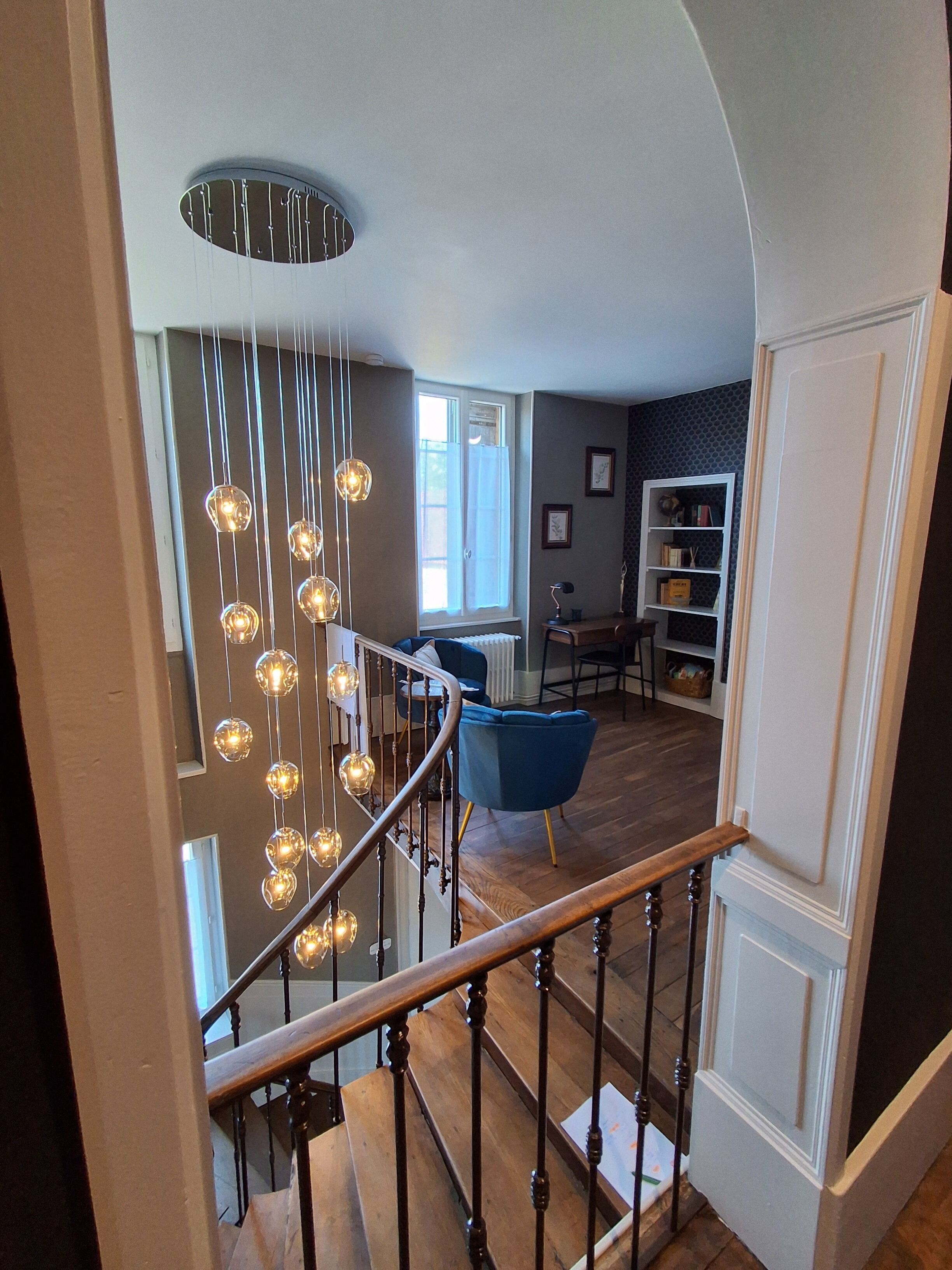 Un escalier avec une rampe en bois et un luminaire moderne.