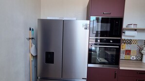 Une cuisine compacte équipée d’un réfrigérateur en acier inoxydable, d’un four à micro-ondes et d’un four encastré dans les meubles.