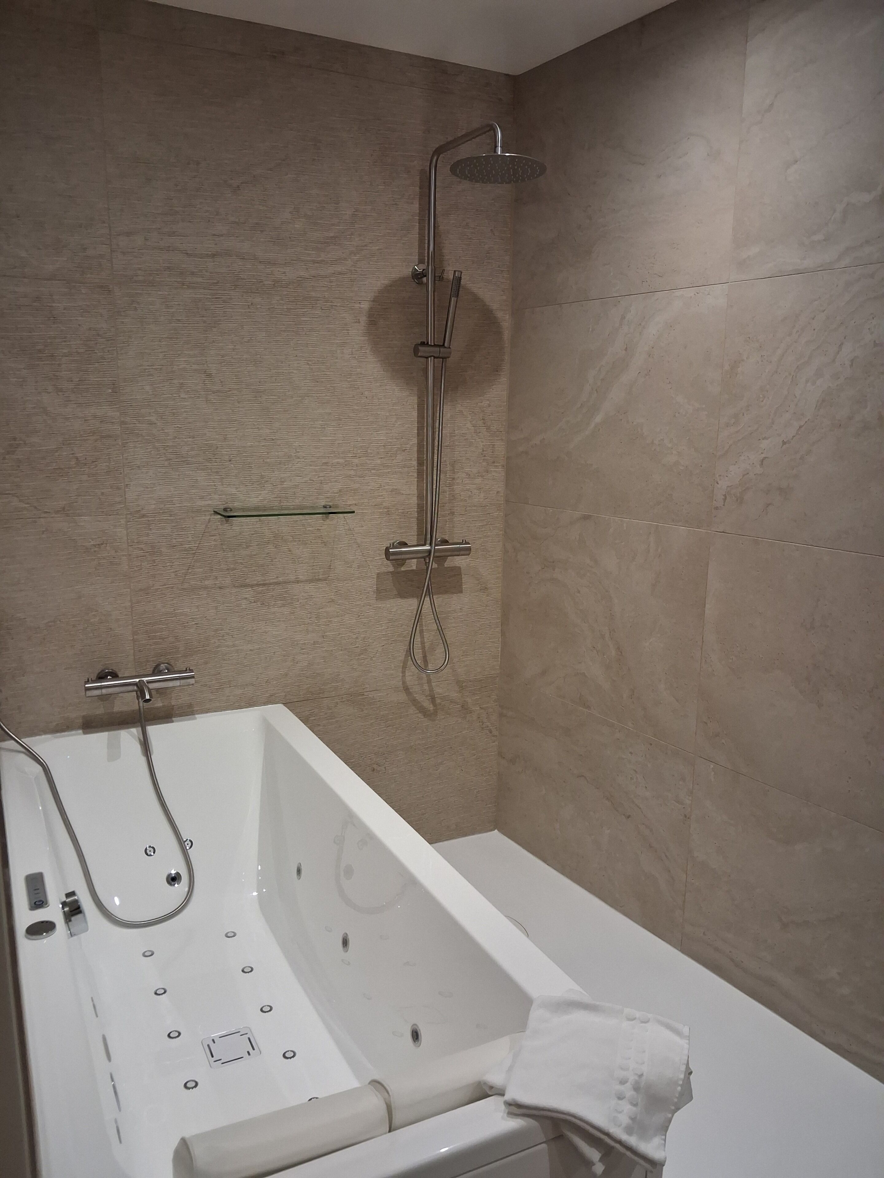 Ein modernes Badezimmer mit Badewanne, Dusche und gefliesten Wänden.