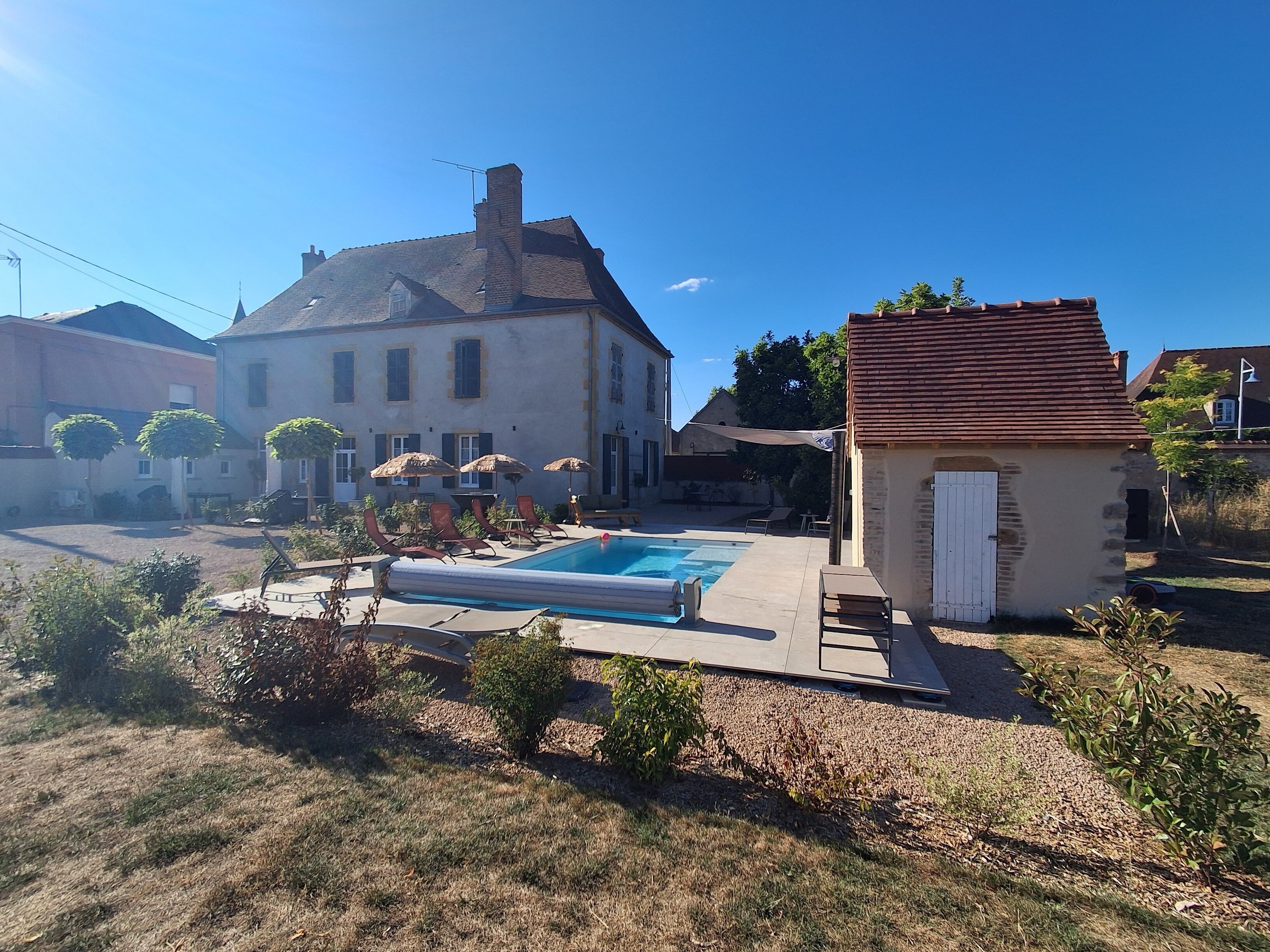 A residential property with a swimming pool, lounge chairs, and a small garden area.