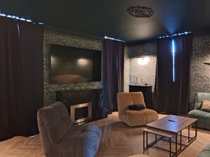 A modern living room with a flat-screen TV, a fireplace, and a sofa. - L'Entre-Deux Eaux Family Home - 5 minutes from Le Pal (Diou)