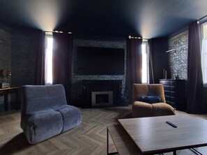 Ein modernes Wohnzimmer mit Kamin, zwei Sofas, einem Couchtisch und einem an der Wand befestigten Fernseher.